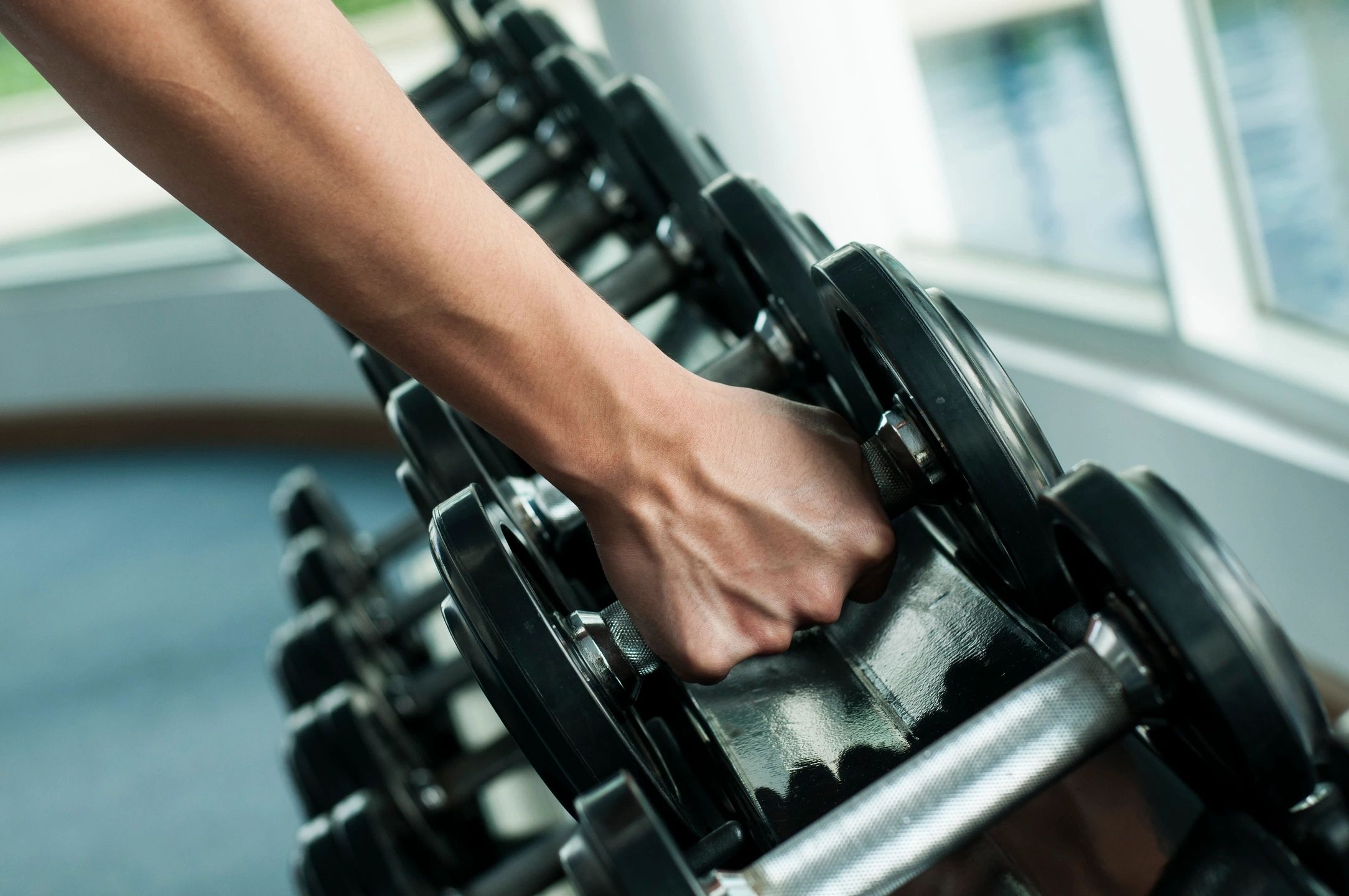 Grabbing a dumbbell from the rack — simple strength training to restart fitness and build everyday confidence.