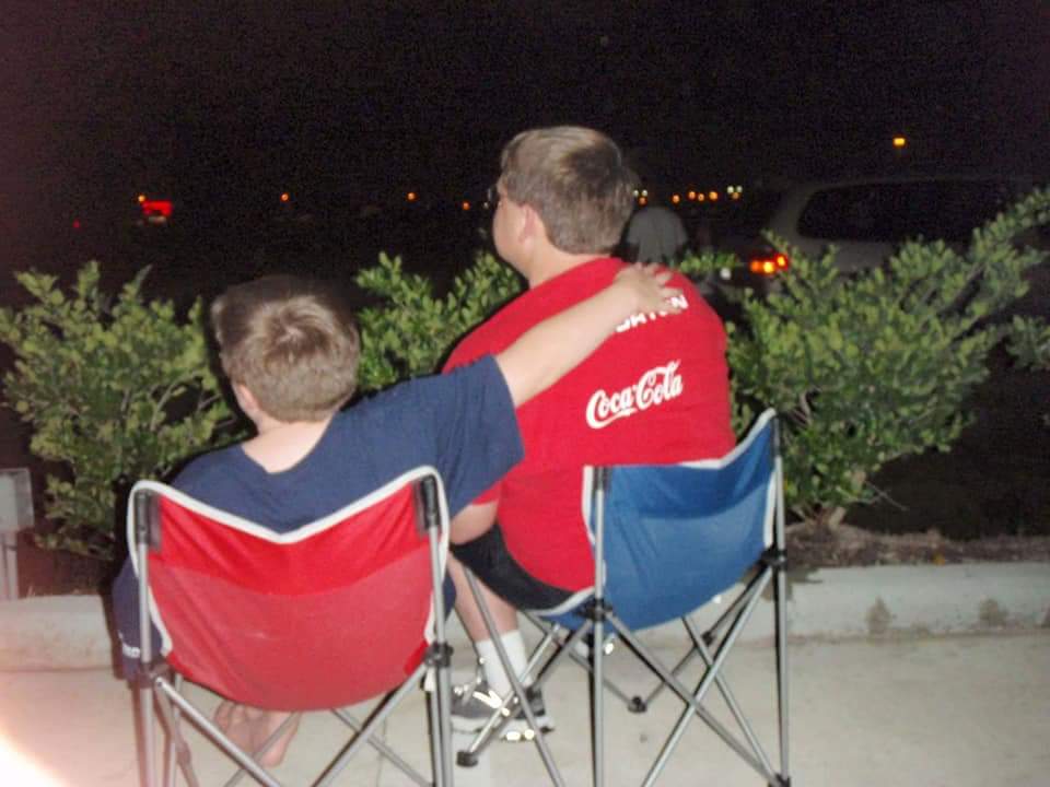 A boy with his arm on his dad's shoulders