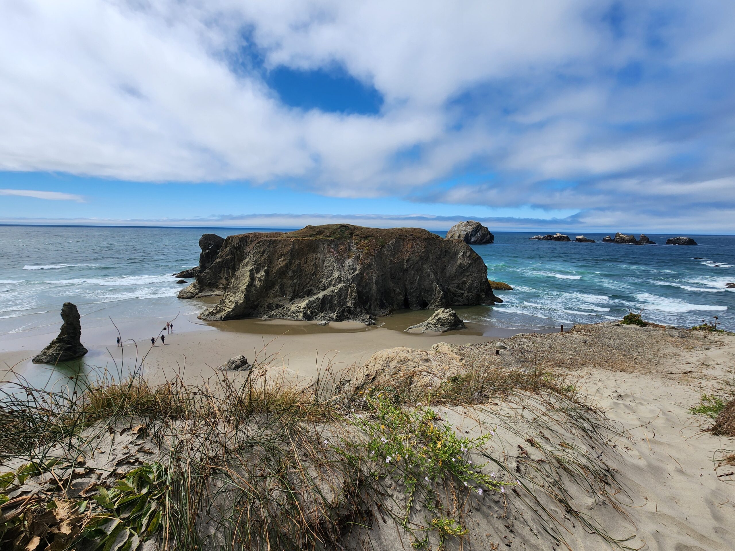 View of Face Rock Scenic Viewpoint from above, with sea stacks, sandy beach, and blue sky along the Oregon coast.