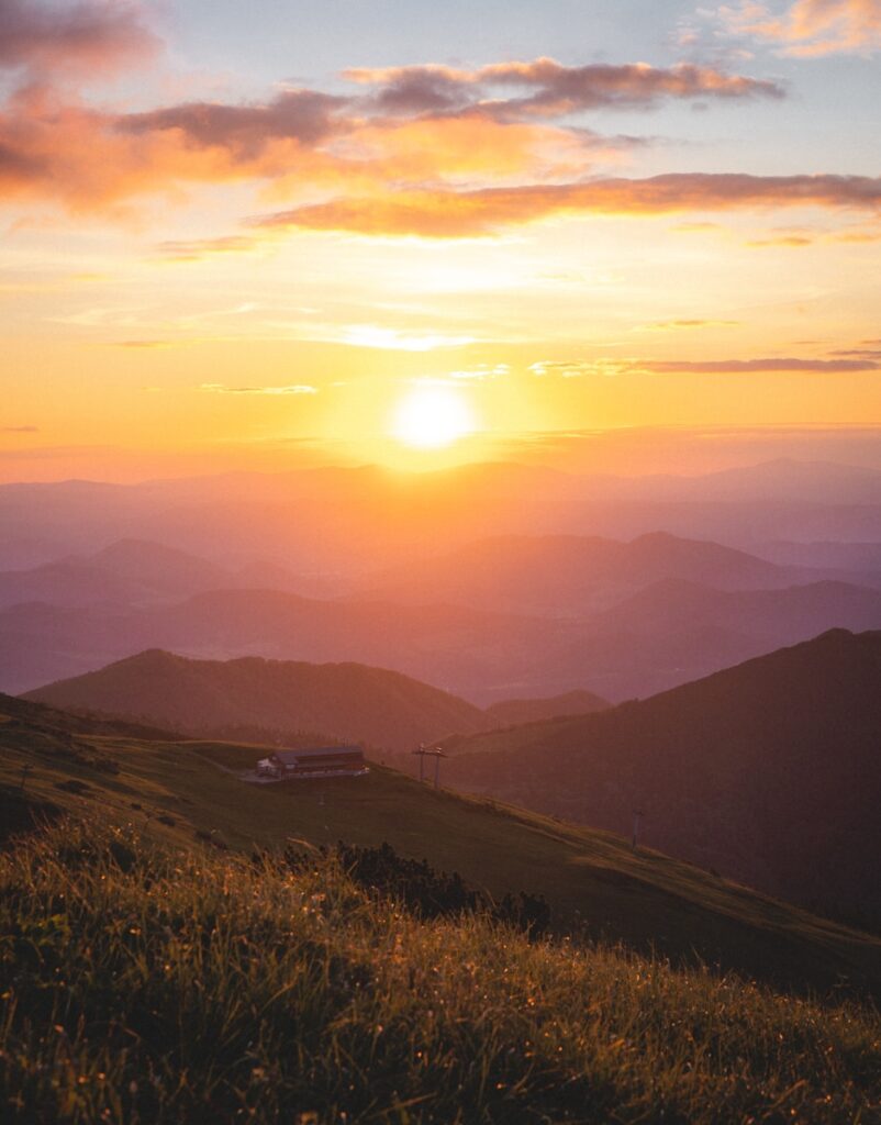 Sunrise casting warm light over a mountain range, symbolizing new beginnings and personal growth
