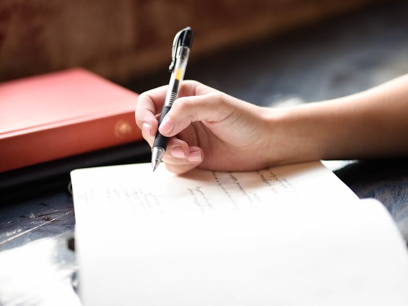 a person writing on a piece of paper with a pen