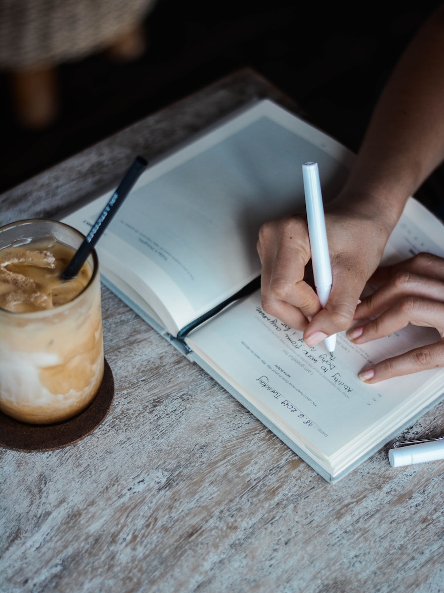 Writing in a journal with coffee nearby as part of a daily habit system.