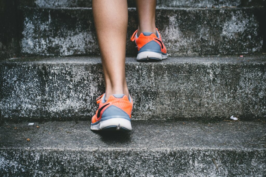Close-up of walking shoes or boots stepping onto a path, forest trail, or boardwalk.
