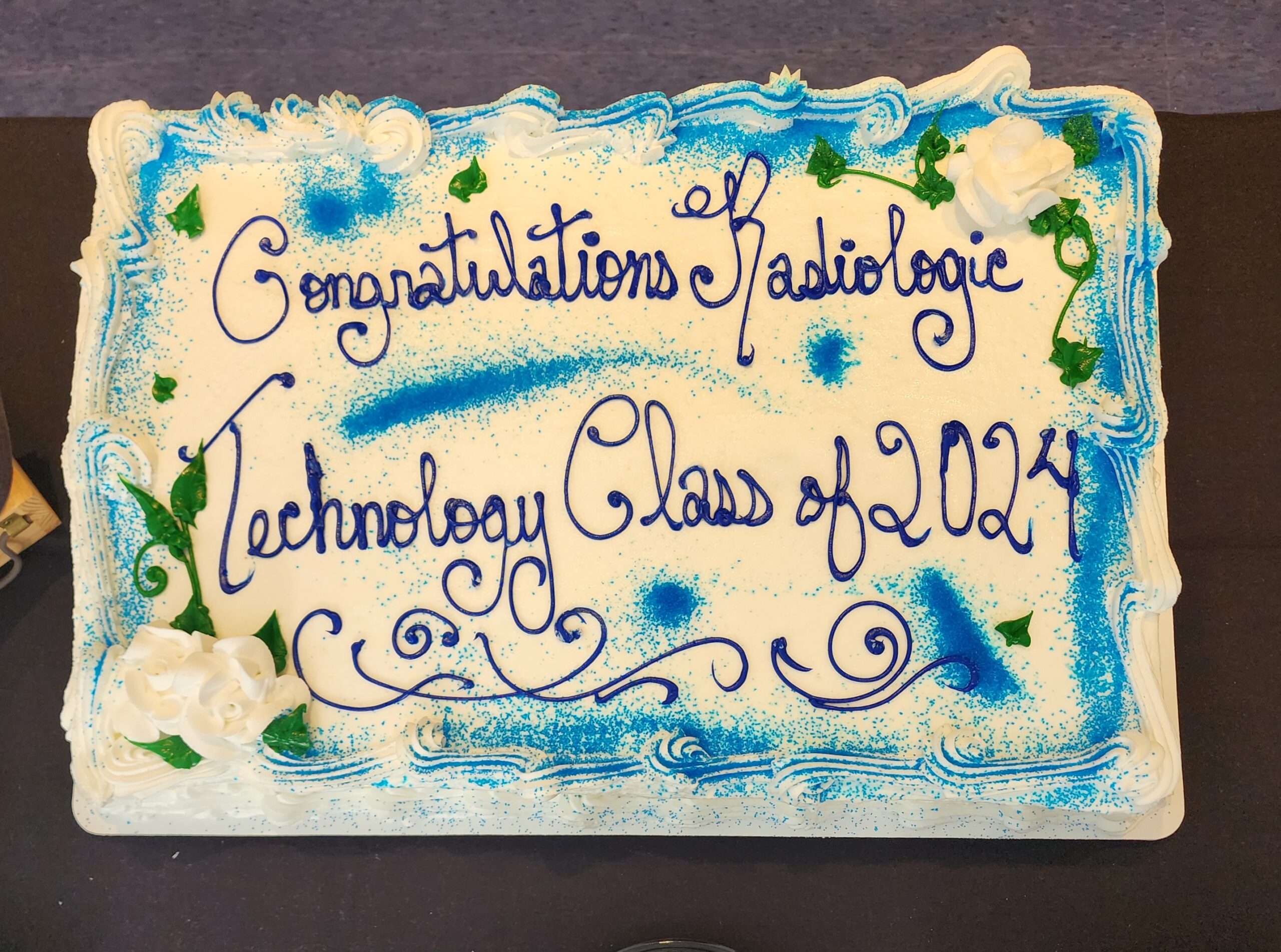 Celebration cake decorated with blue and green icing, reading ‘Congratulations Radiologic Technology Class of 2024.
