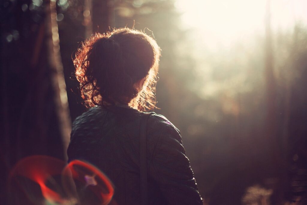 Person in a forest at sunrise, pausing in the light, illustrating reflection, creativity, and midlife reinvention.