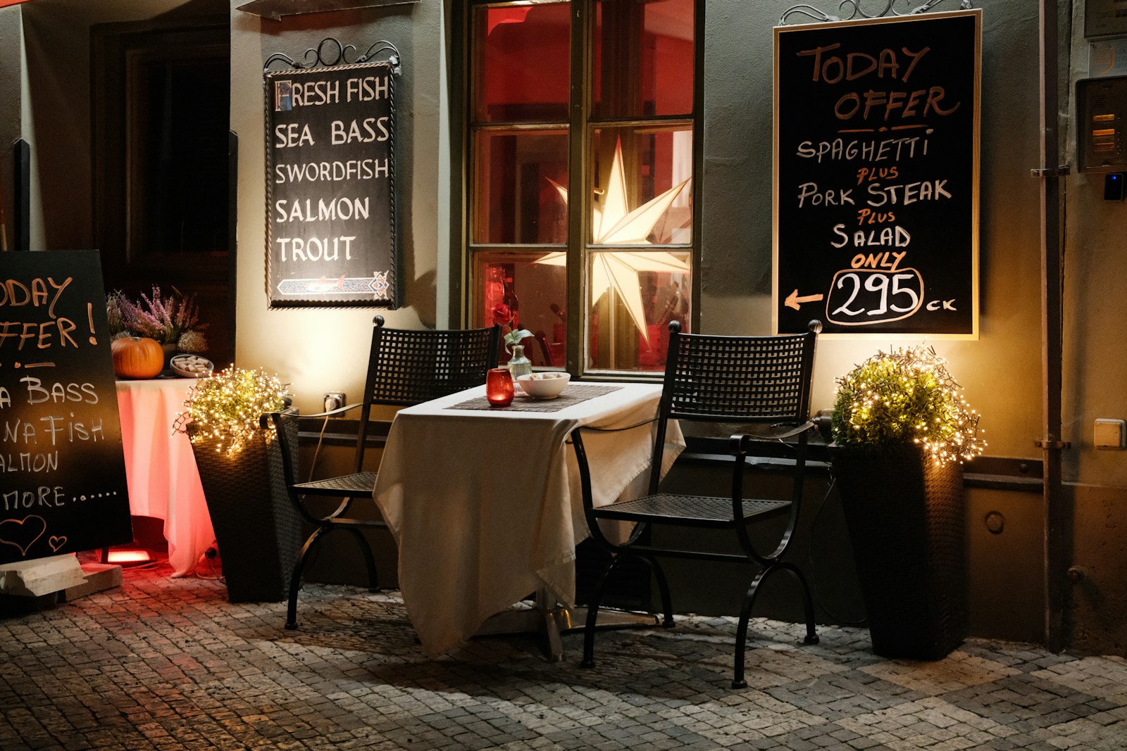 Restaurant table set outside at night or a holiday meal with simple whole foods like beef, eggs, and salmon.
