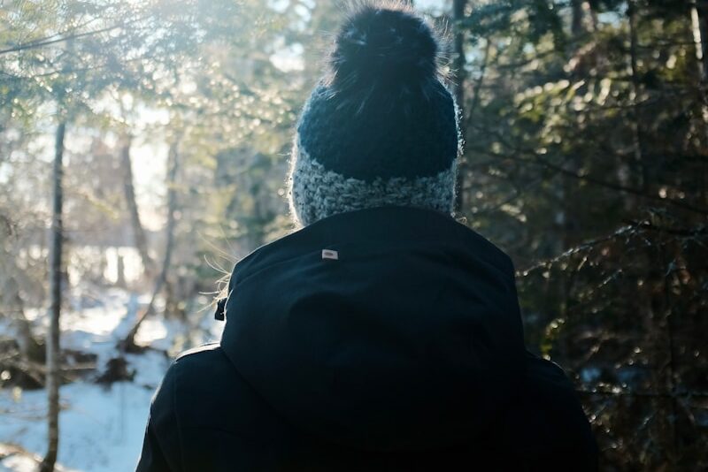 person in black jacket standing in front of trees during daytime
