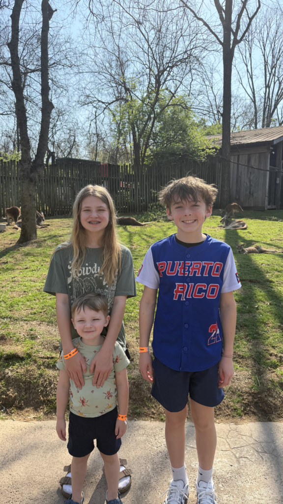 Three grandkids exploring the Nashville Zoo together during a family road trip