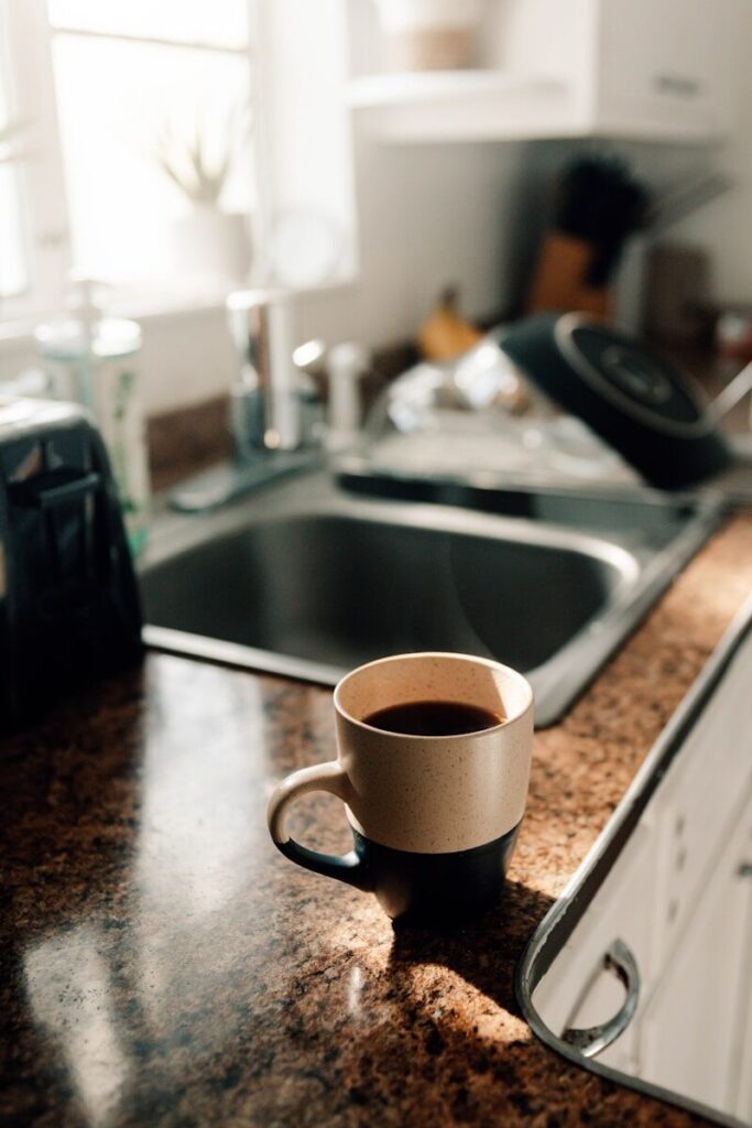 a cup of coffee sitting on top of a kitchen counter, being present in the moment.