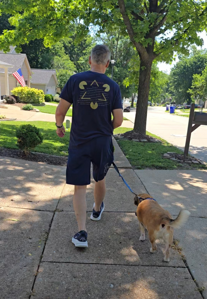 Tom walking on a neighborhood path with one of the dogs on a summer morning.