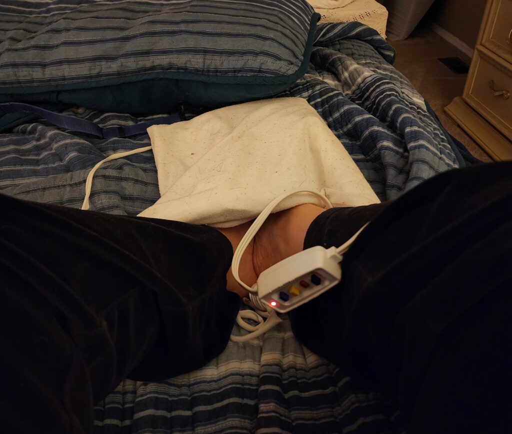 Krista resting with a heating pad after a long day of radiologic technology school and clinicals